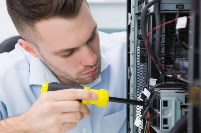 Technician using a screwdriver to work on internal computer components.