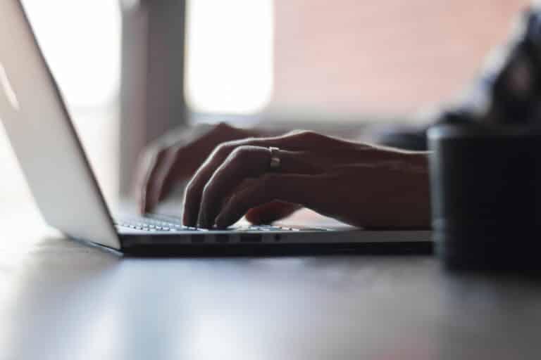 Close-up of hands typing on a laptop keyboard.