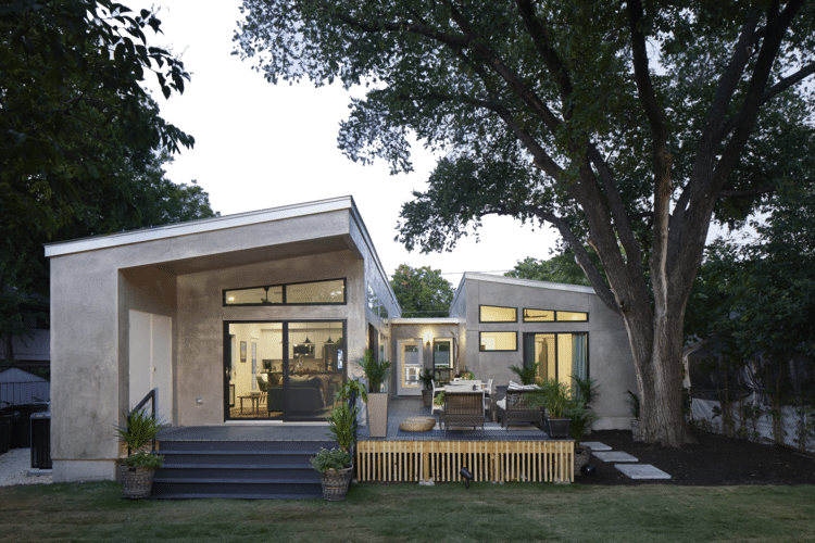 Modern home with warm lighting and large windows, showcasing the comfort and convenience of smart home technology during holiday hosting.