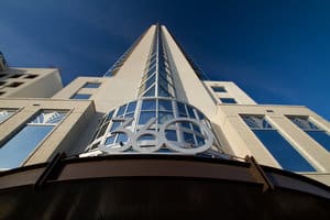 A low-angle view of a modern high-rise building with a 360 sign at the entrance.