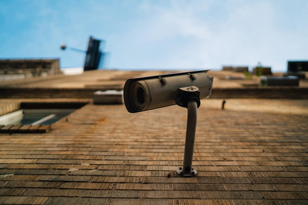 Security camera mounted on a brick wall, viewed from below.