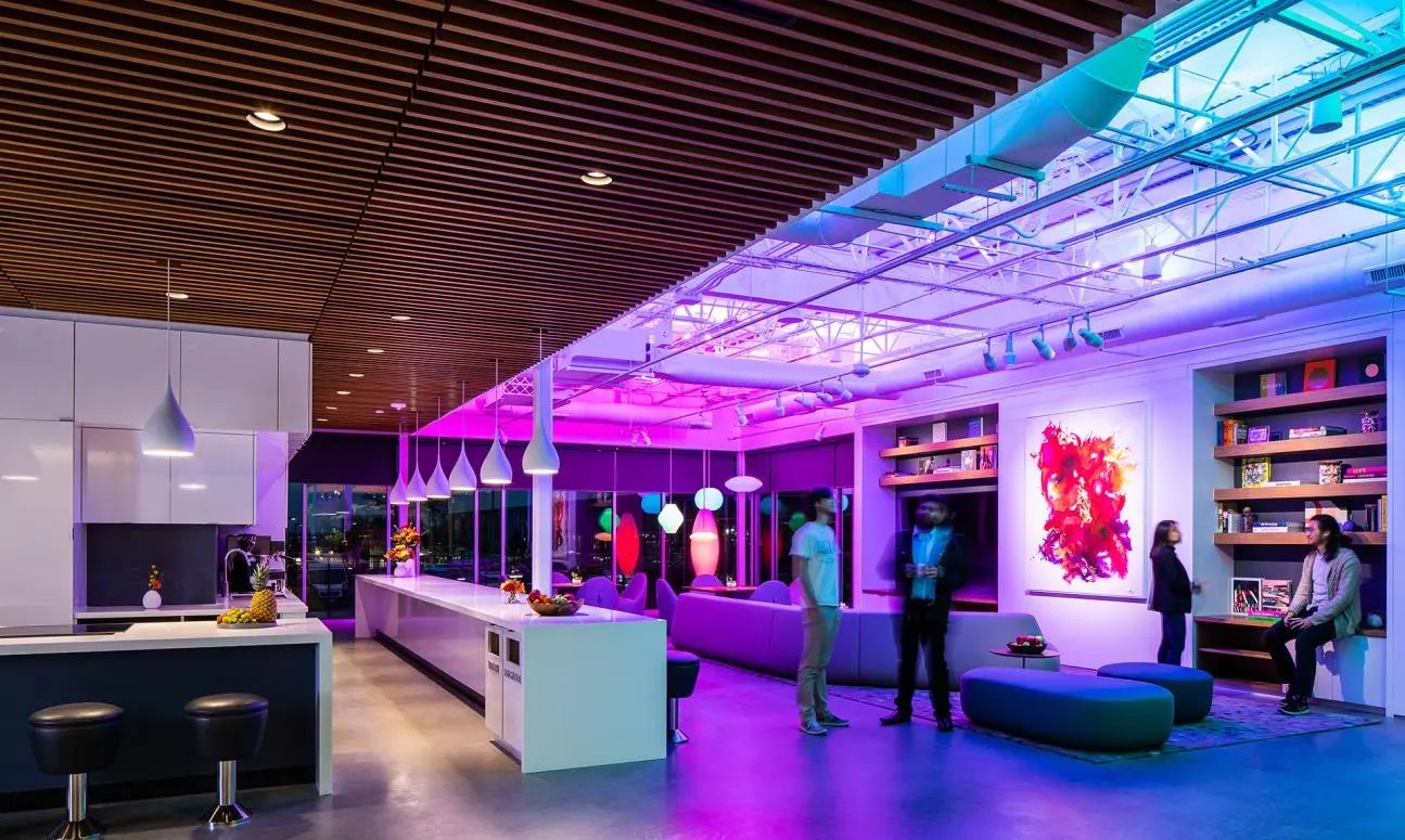 Collaboration Studio at Ketra headquarters washed in violet and blue light, with pendants and a long kitchen bar