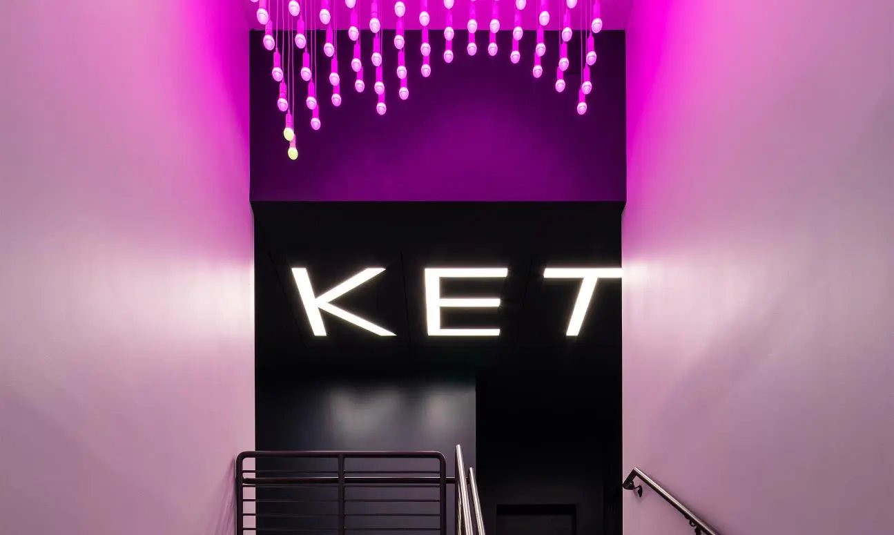 Stairwell at Ketra headquarters with a hanging light sculpture and the Ketra sign glowing in magenta