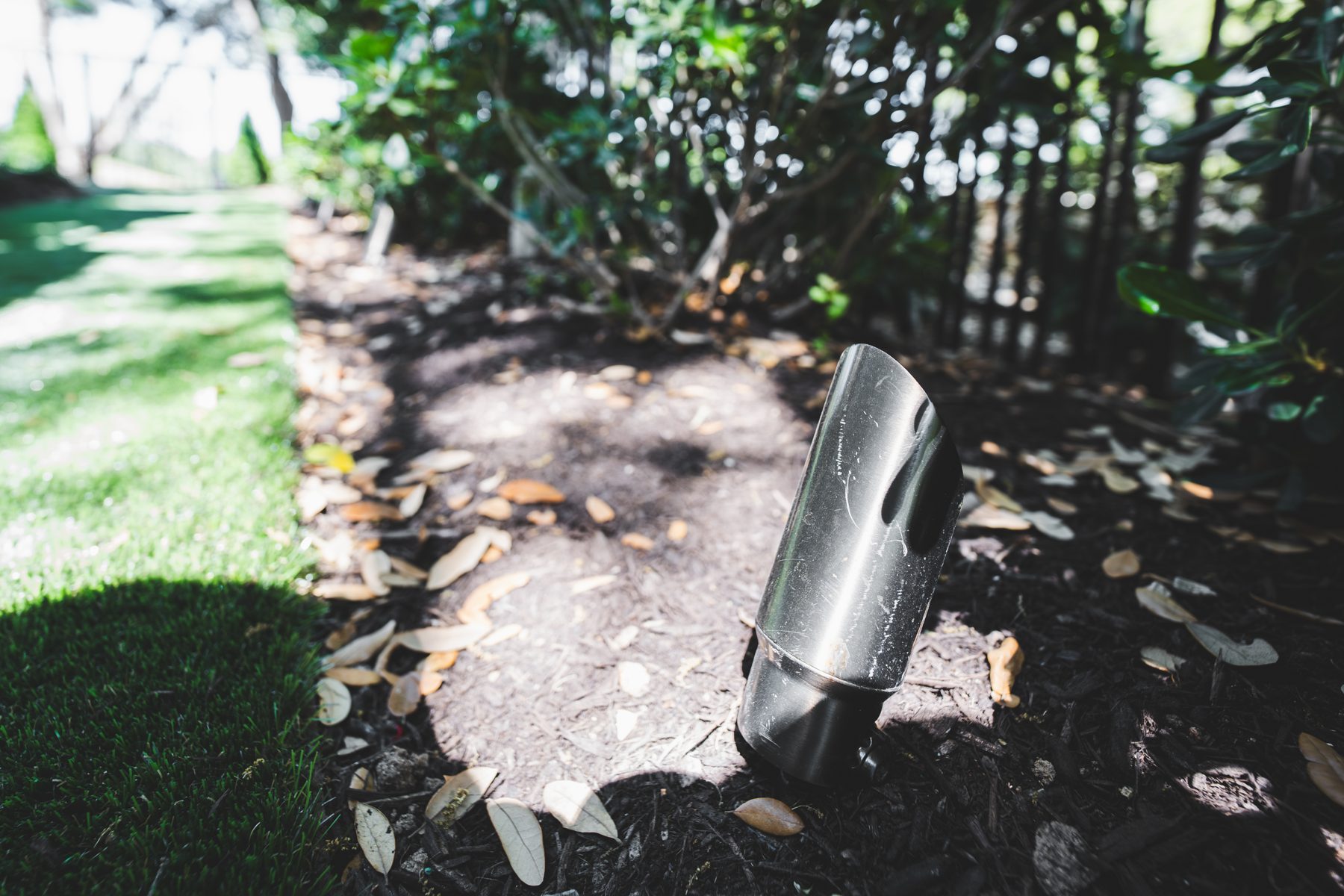 Landscape light fixture in a mulched bed beside a lawn
