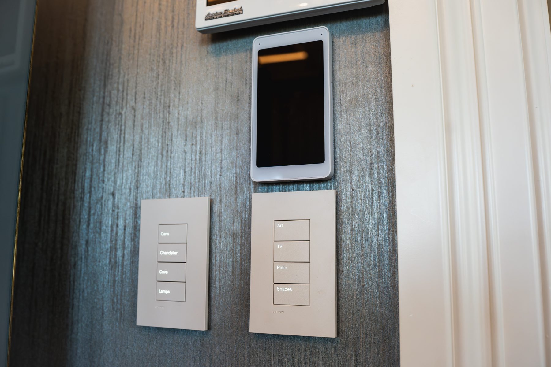 Wall touchscreen above two engraved Palladiom keypads on a dark wall