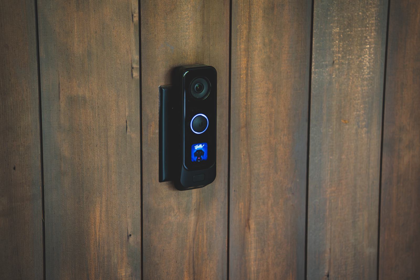 Video doorbell on a dark wood-paneled entry wall